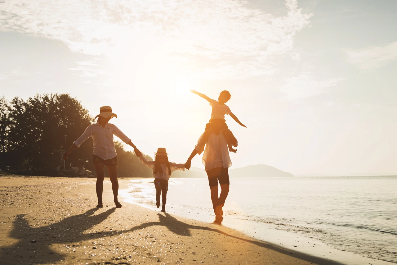 Familie mit zwei Kindern geht freudig am Strand spazieren